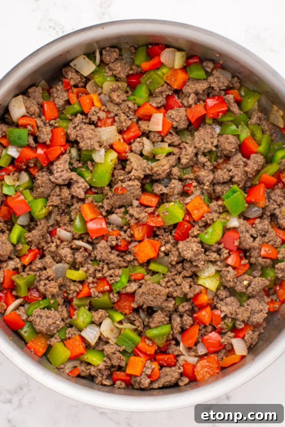 ground beef, diced peppers and onions in a skillet 