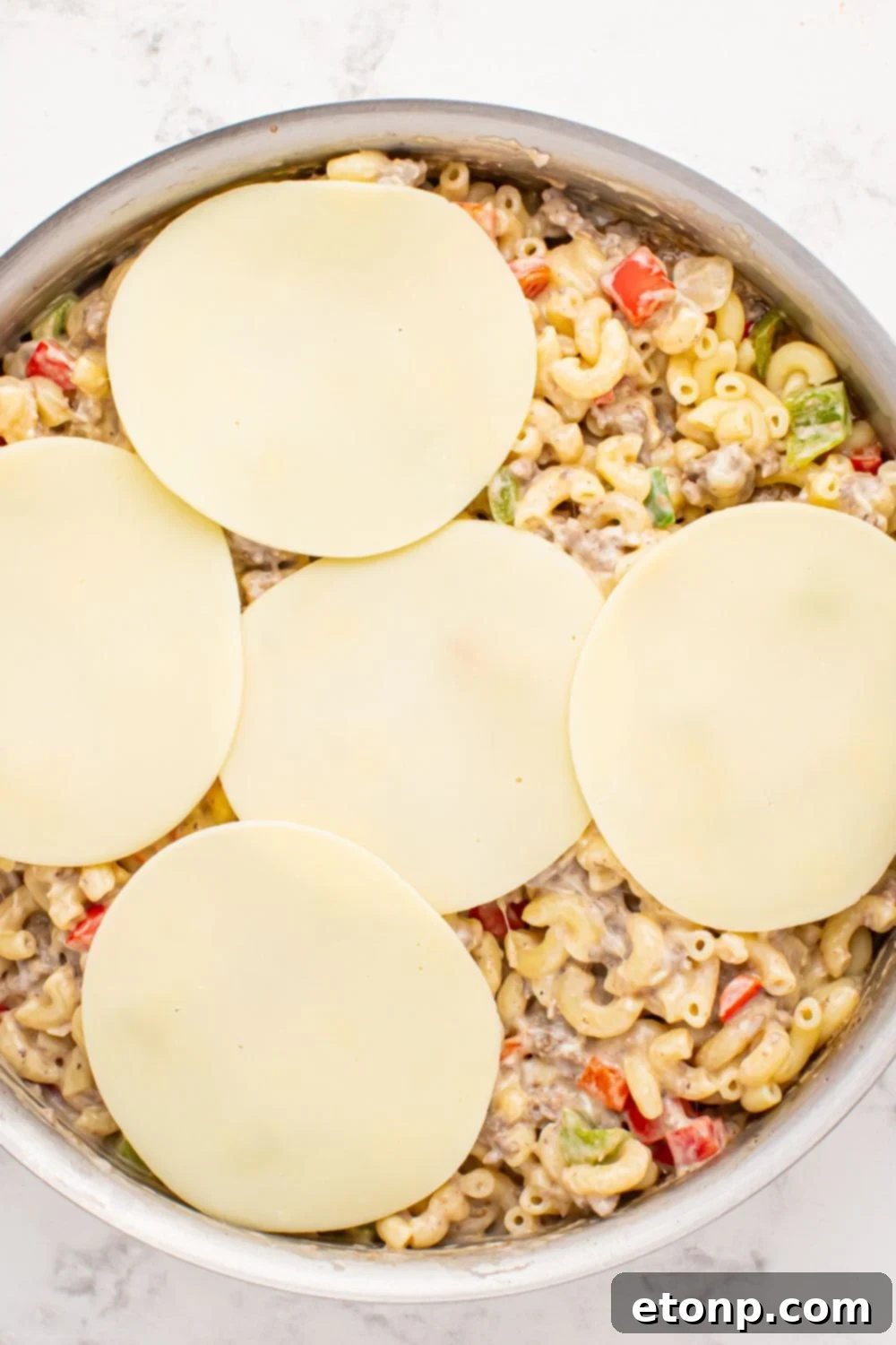 provolone cheese slices on top of the Philly Cheesesteak Pasta mixture in skillet