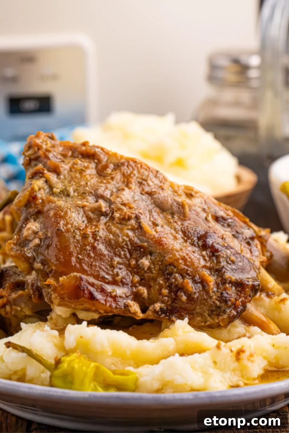 A beautifully plated dish of baby back ribs, creamy mashed potatoes, and bright pepperoncini peppers, with a softly blurred background.