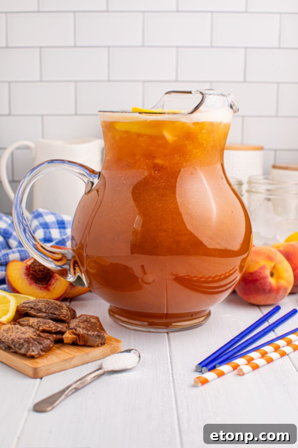 Southern Peach Infusion 11 Peach Sweet Tea in a large pitcher with tea bags peaches, and straws around the table
