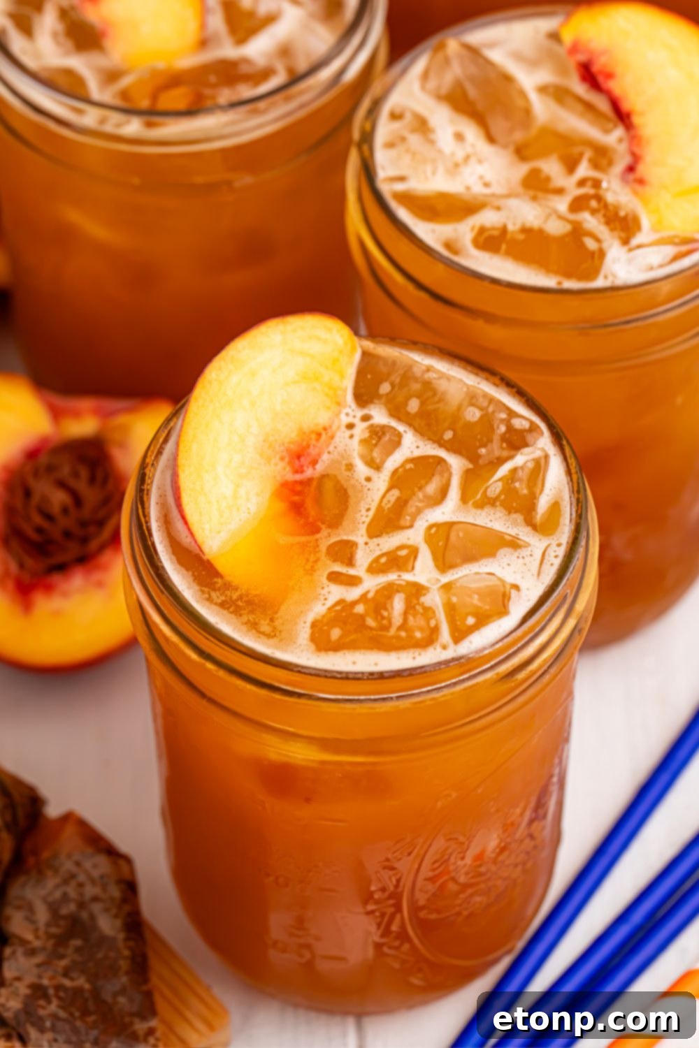 Southern Peach Infusion 13 Peach Sweet Tea in mason jars with fresh peach slices in each glass sitting on top of the ice