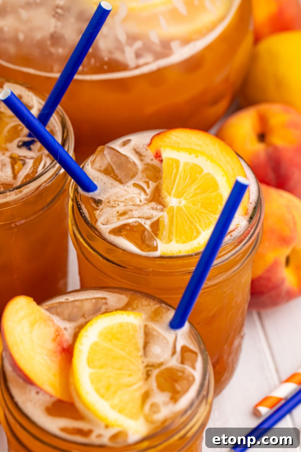Southern Peach Infusion 16 glasses of tea sitting on table with whole peaches in the background to show this is a peach tea recipe