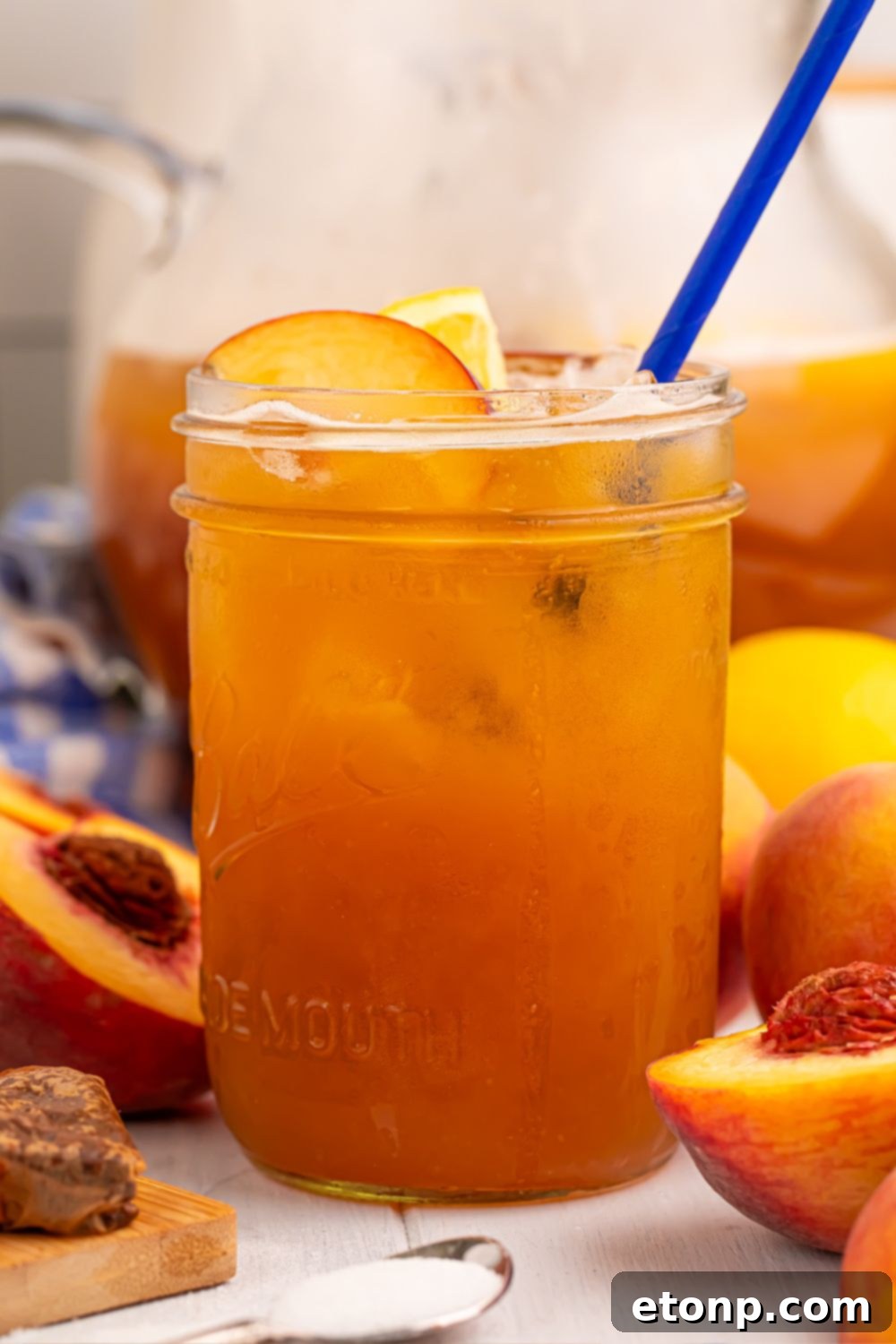 Southern Peach Infusion 17 side view of glass full of peach sweet tea with fruit around the glass on table