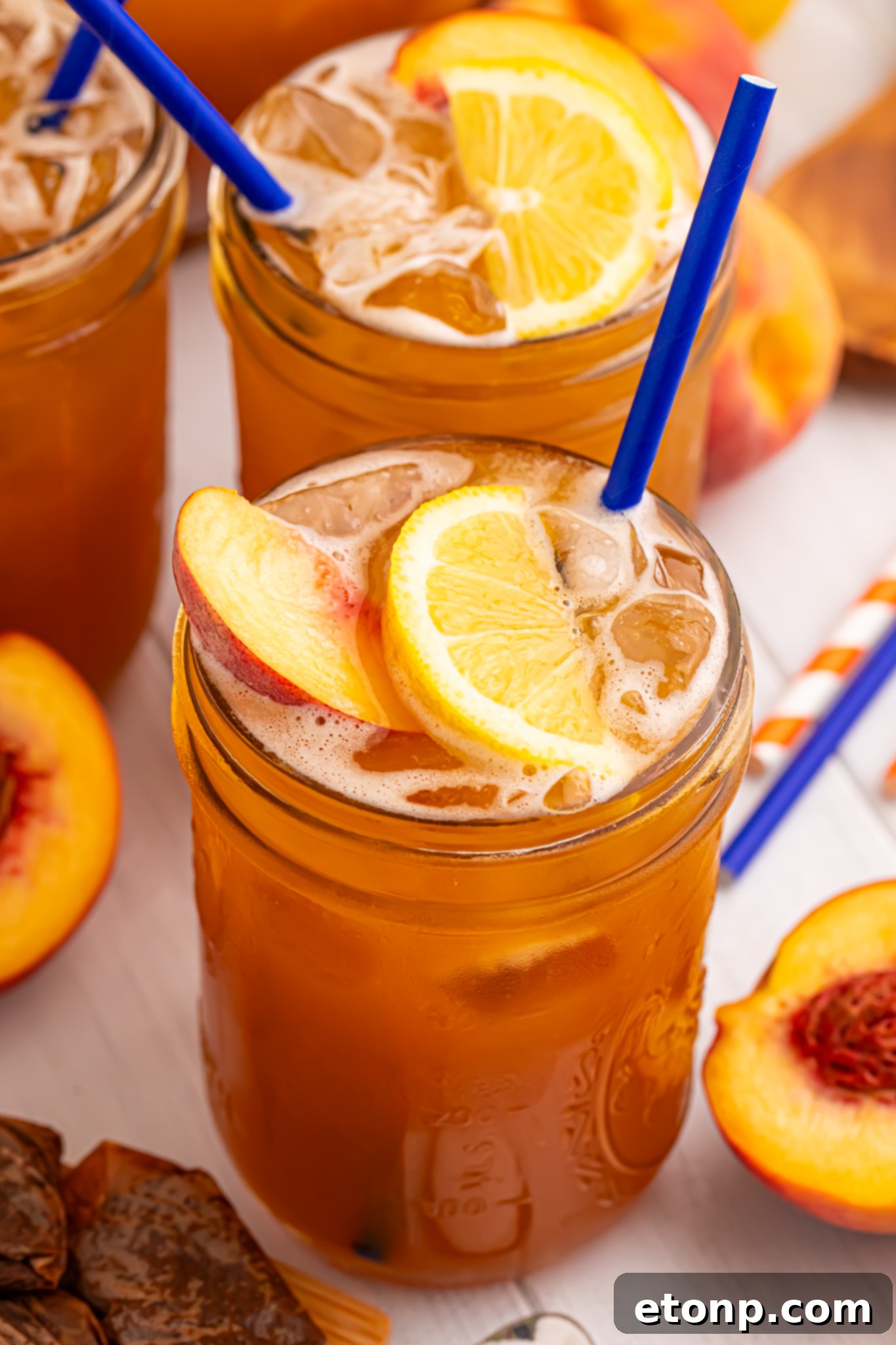 Southern Peach Infusion 18 side view of glass full of peach sweet tea with fruit around the glass on table