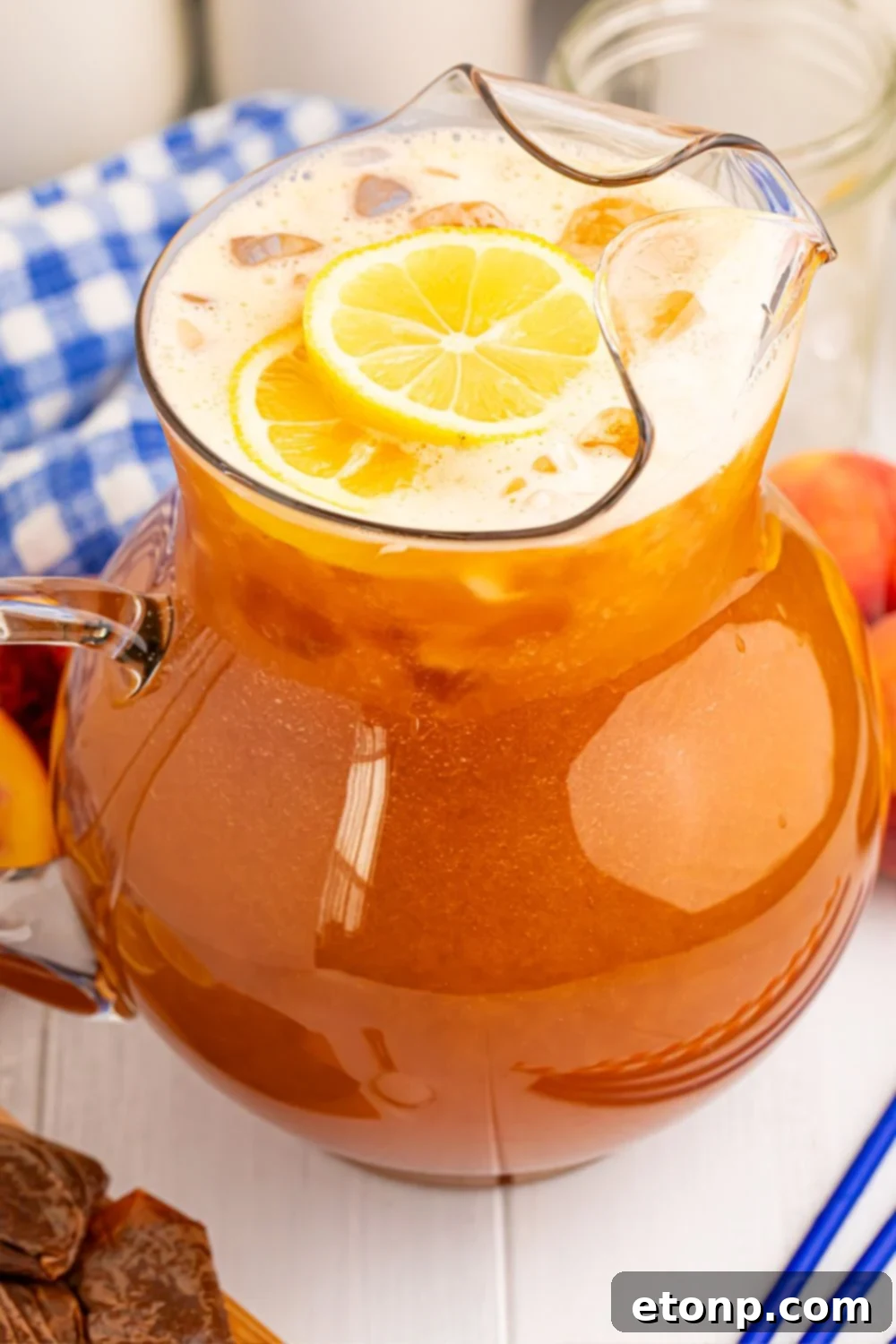 Southern Peach Infusion 4 Peach Sweet Tea in a large pitcher on table with a blue napkin and blue straws beside it