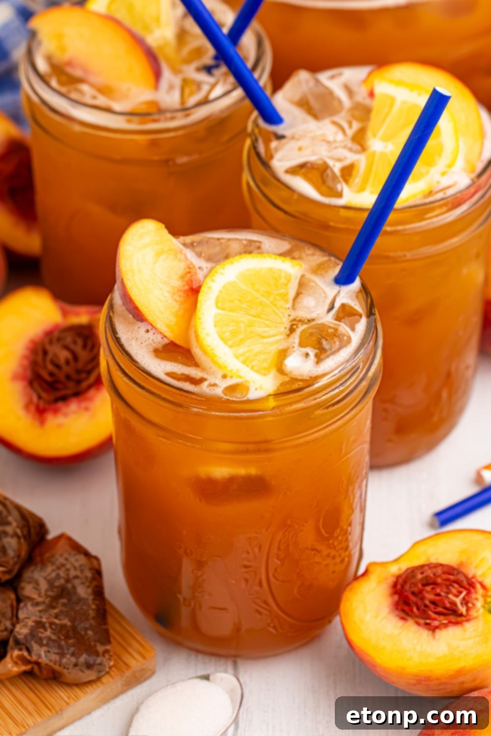 Southern Peach Infusion 5 mason jars with Sweet peach tea in each glass and fresh peaches around the glasses on table