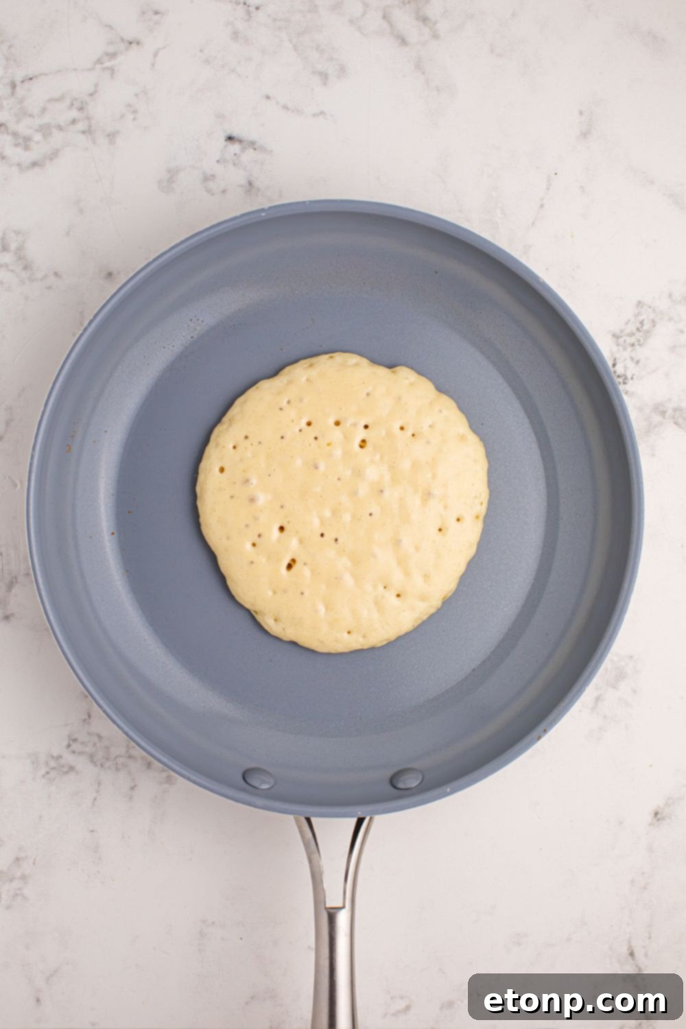 Uncooked pancake batter in a skillet, heating up