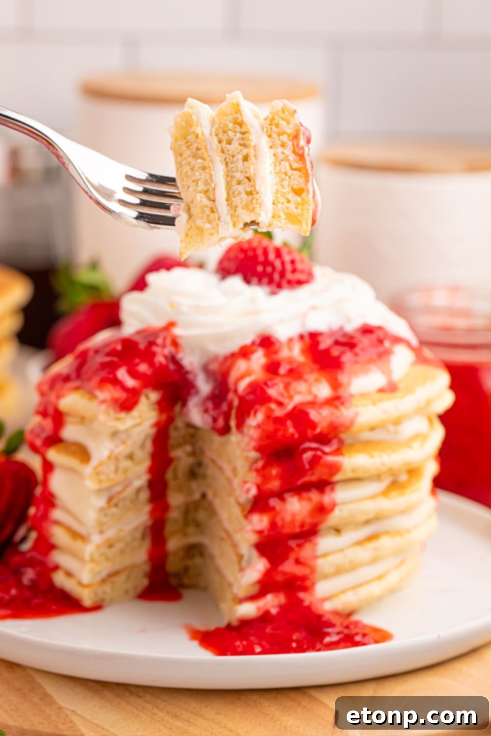 Strawberry Cheesecake Pancakes on a plate with a fork taking a bite