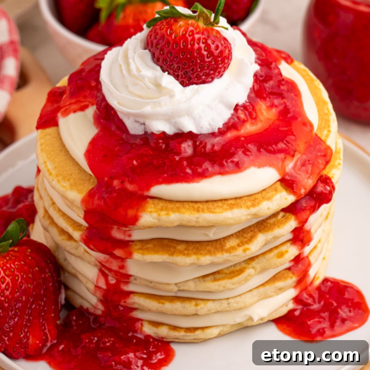 Close-up of Strawberry Cheesecake Pancakes with whipped cream and a whole strawberry on top