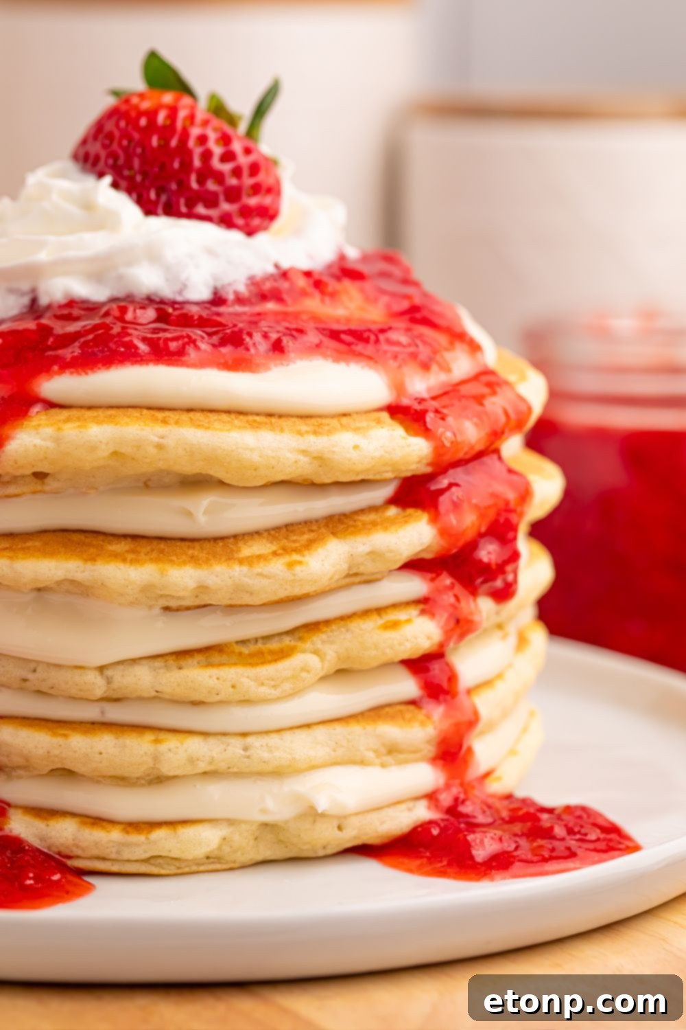 Side view of pancakes with cream cheese spread and strawberries on top