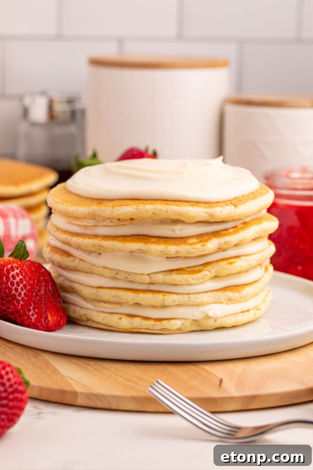Cheesecake mixture spread on top of stacked pancakes for Strawberry Cheesecake Pancakes