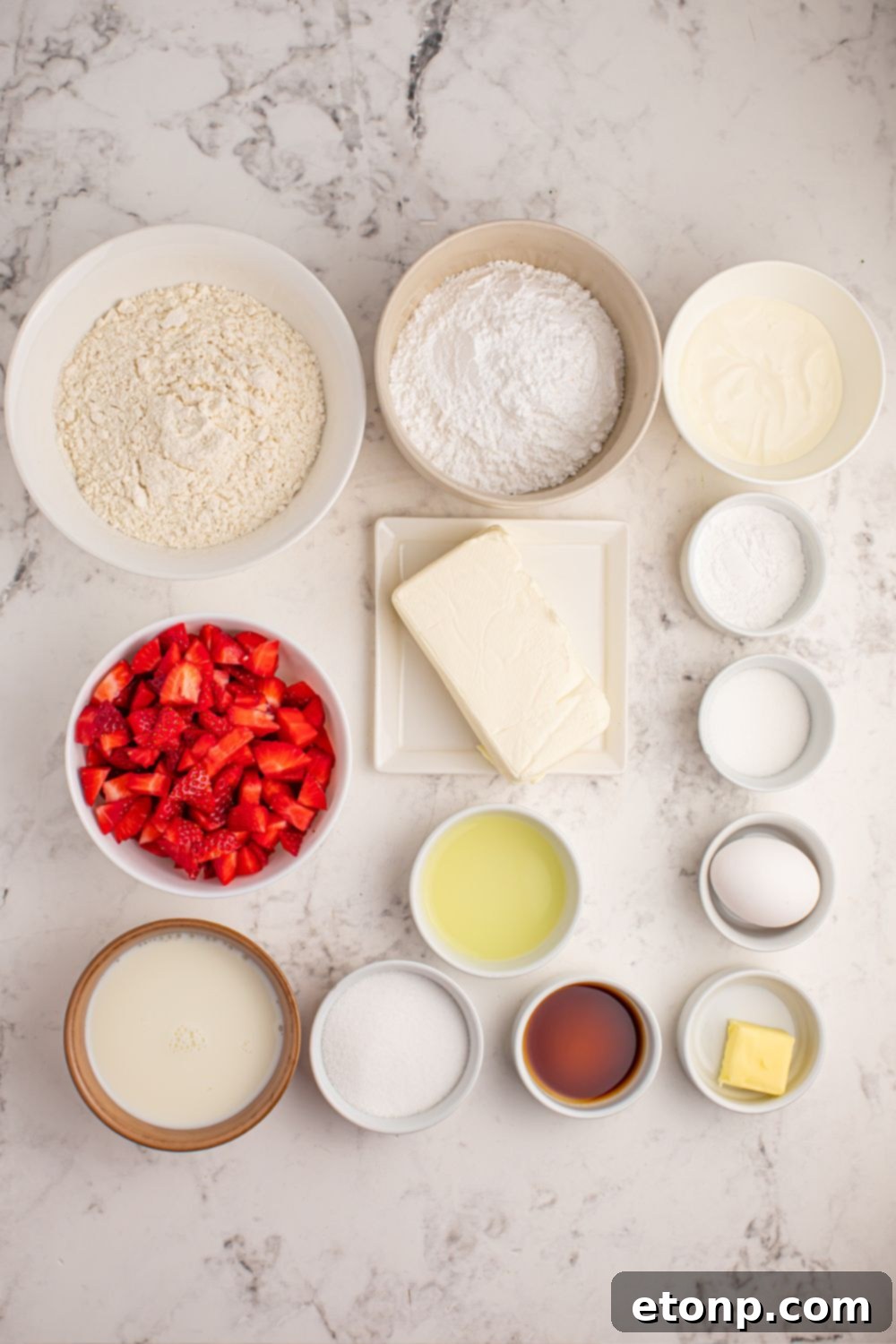 Ingredients for Strawberry Cheesecake Pancakes laid out in individual bowls on a marble table