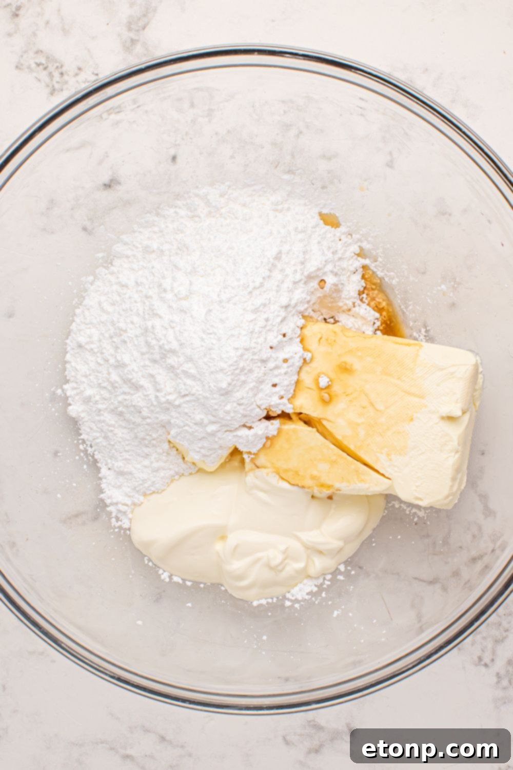 Creamy cheesecake mixture in a glass bowl on a marble counter