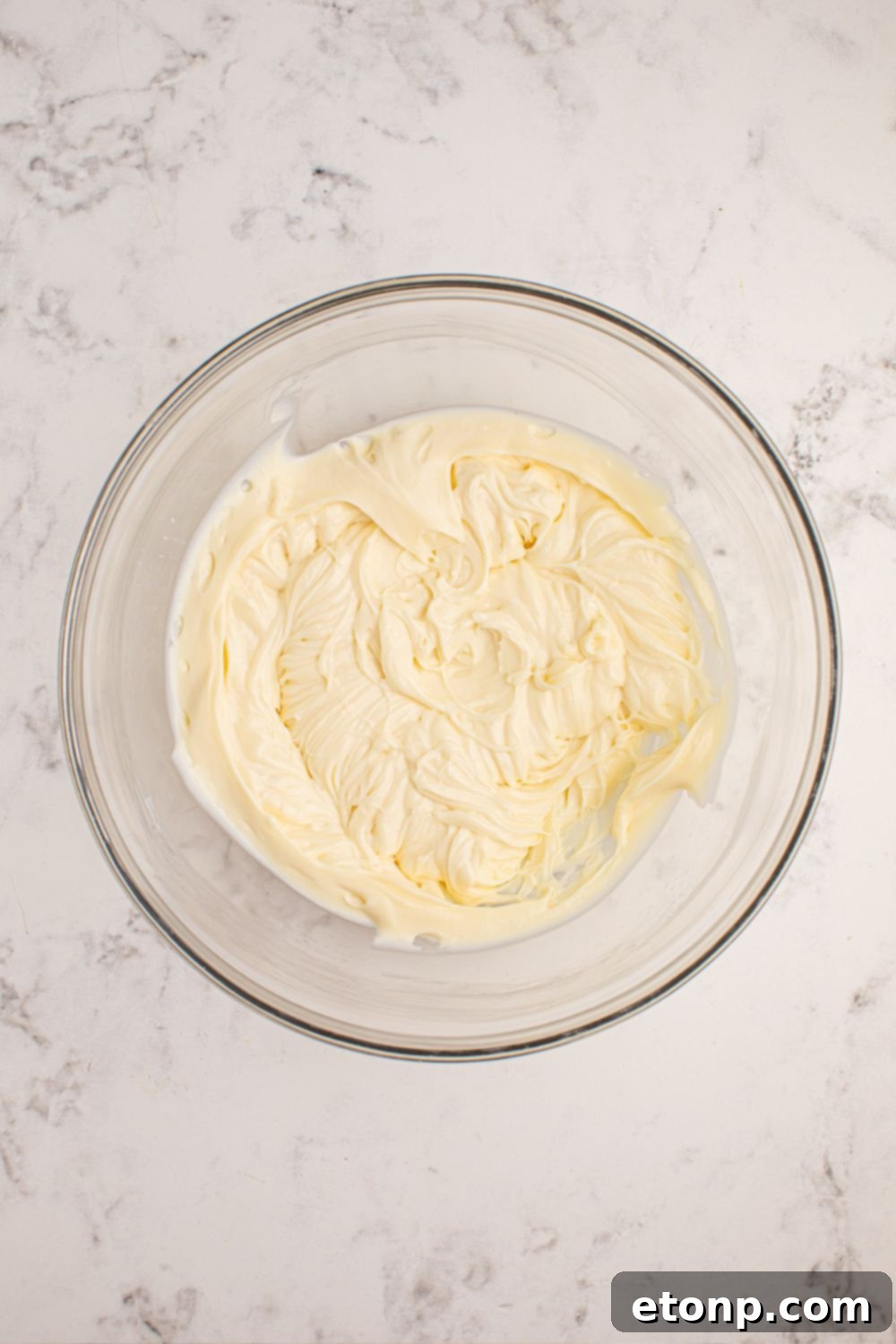 Well-mixed cheesecake filling in a glass bowl