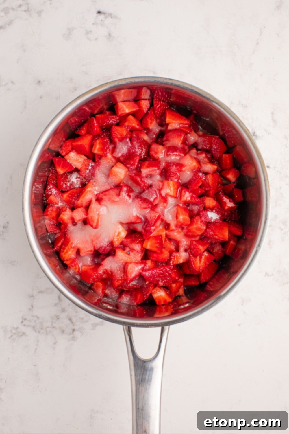 Diced strawberries and sugar combined in a pan on the counter