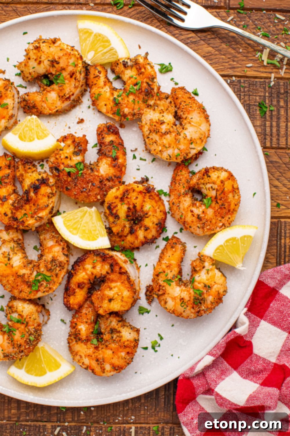 A serving of Cajun grilled shrimp on a plate, showcasing the rich seasoning and a side of fresh lemon slices, emphasizing the dish's flavor.