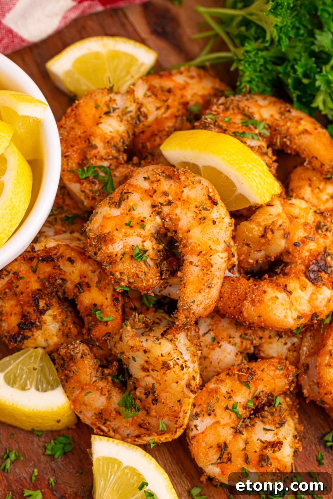 A vibrant pile of perfectly grilled Cajun shrimp, glistening with seasoning, served alongside bright yellow lemon slices, ready to be enjoyed.