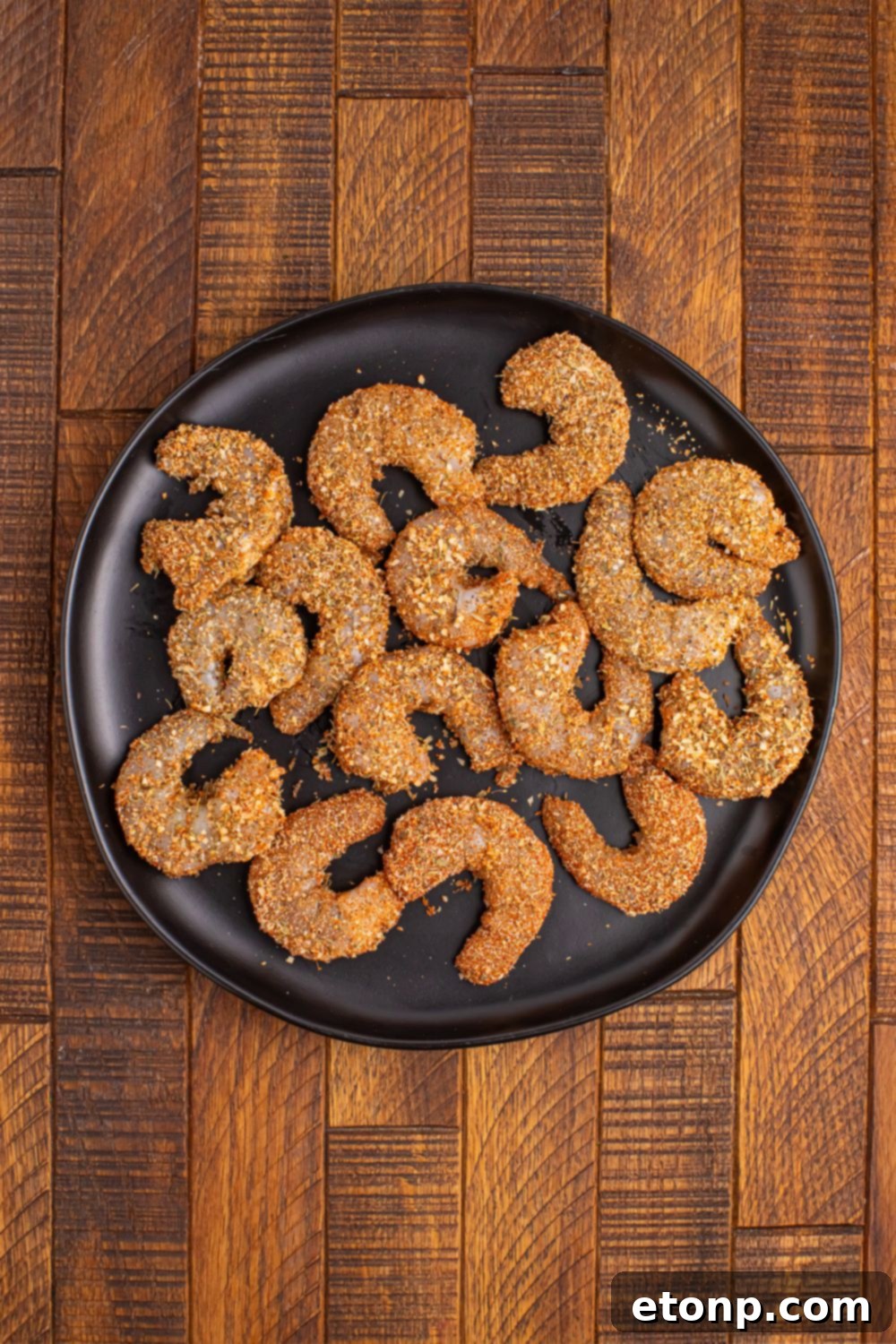 Fresh, raw large shrimp, peeled and deveined, ready for seasoning and grilling, arranged neatly on a plate.