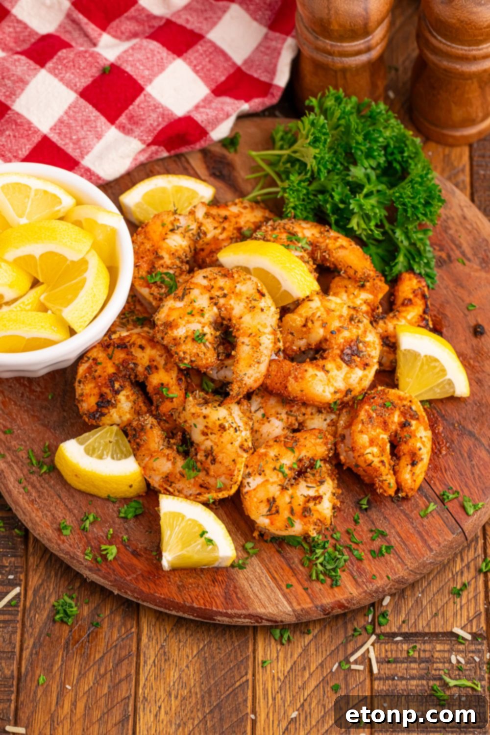 A plate of perfectly cooked Cajun grilled shrimp resting on a rustic wooden counter, with a bowl of fresh lemons in the background, ready for serving.
