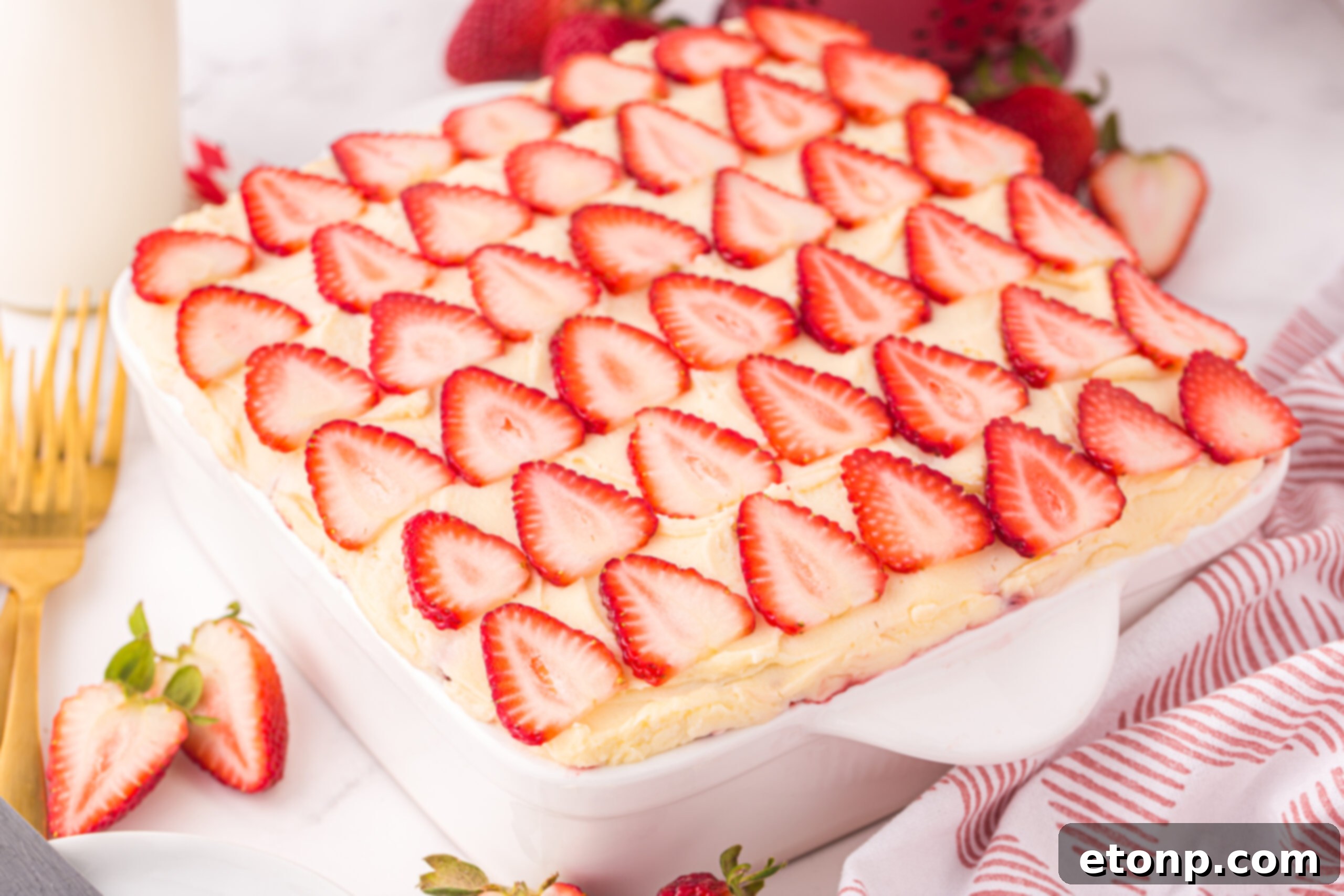 Strawberry Dream Tiramisu 11 A pan of freshly assembled Strawberry Tiramisu, chilling on a table with a kitchen towel in the background.