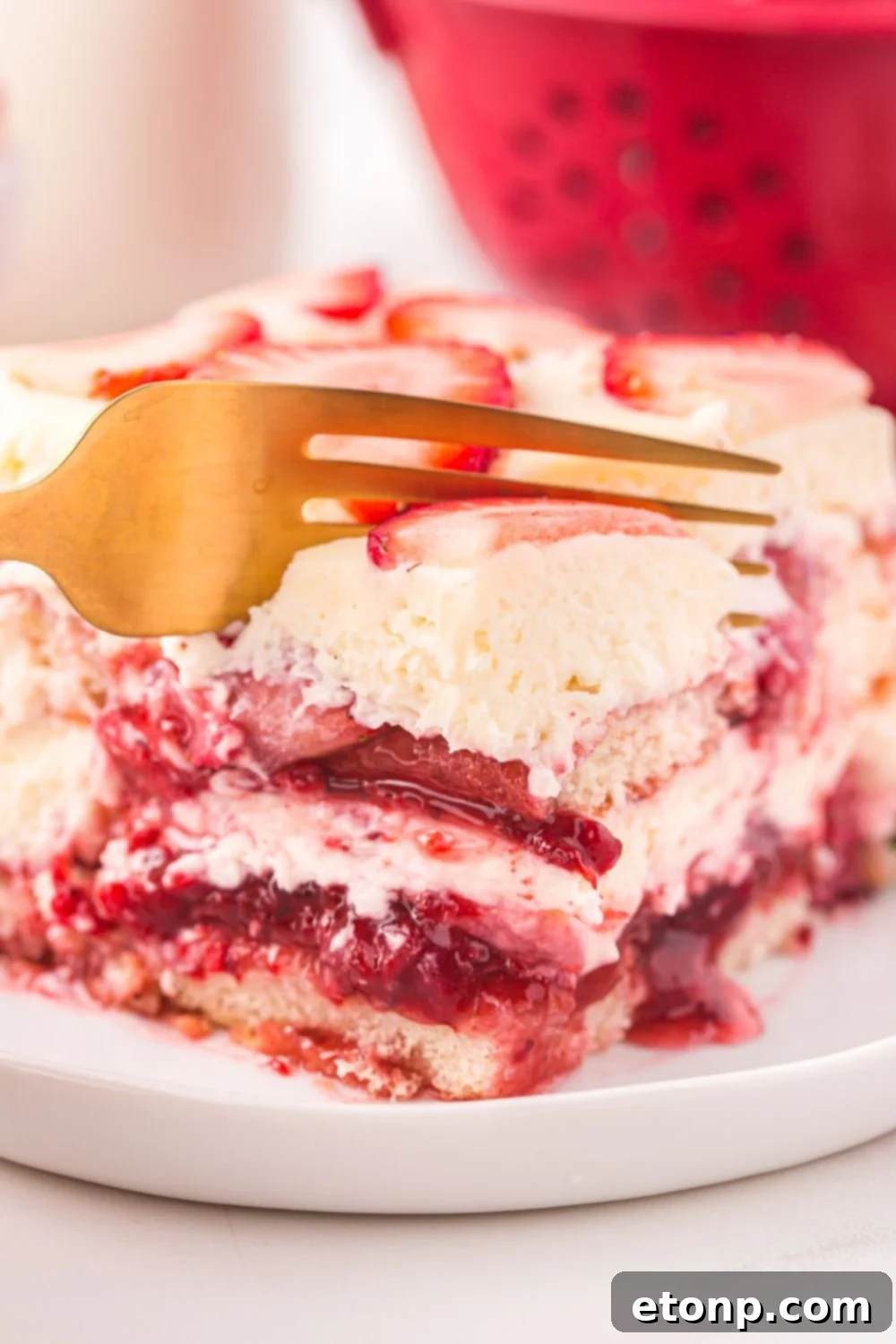 Strawberry Dream Tiramisu 13 A gold fork cutting into a piece of Strawberry Tiramisu, highlighting its soft layers.