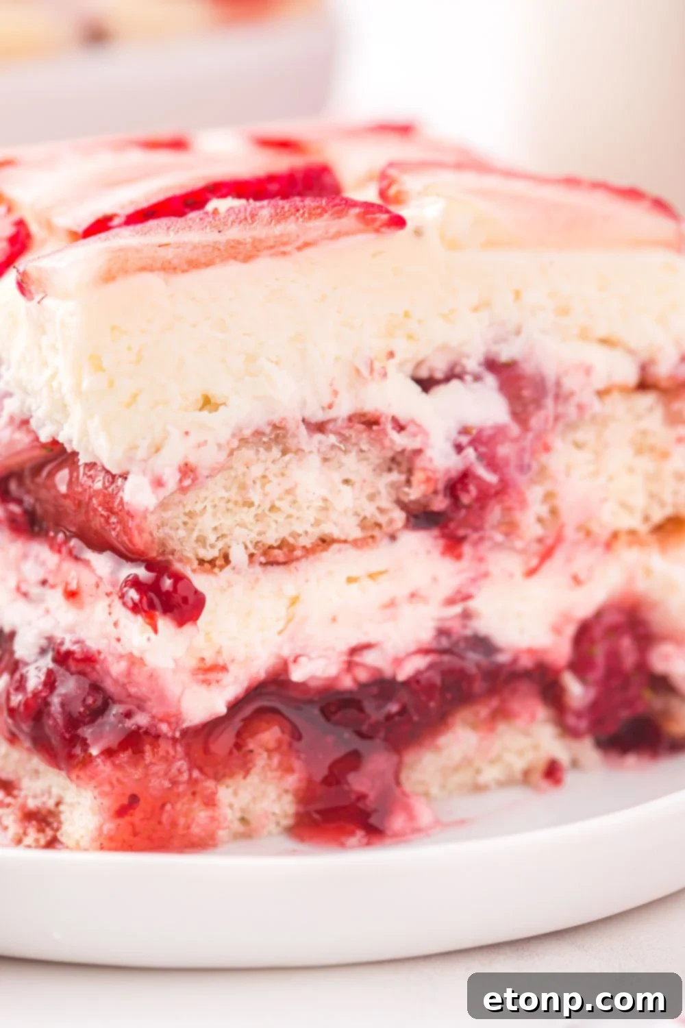 Strawberry Dream Tiramisu 15 A slice of Strawberry Tiramisu on a plate, with a tall glass of milk in the background, inviting a delicious break.