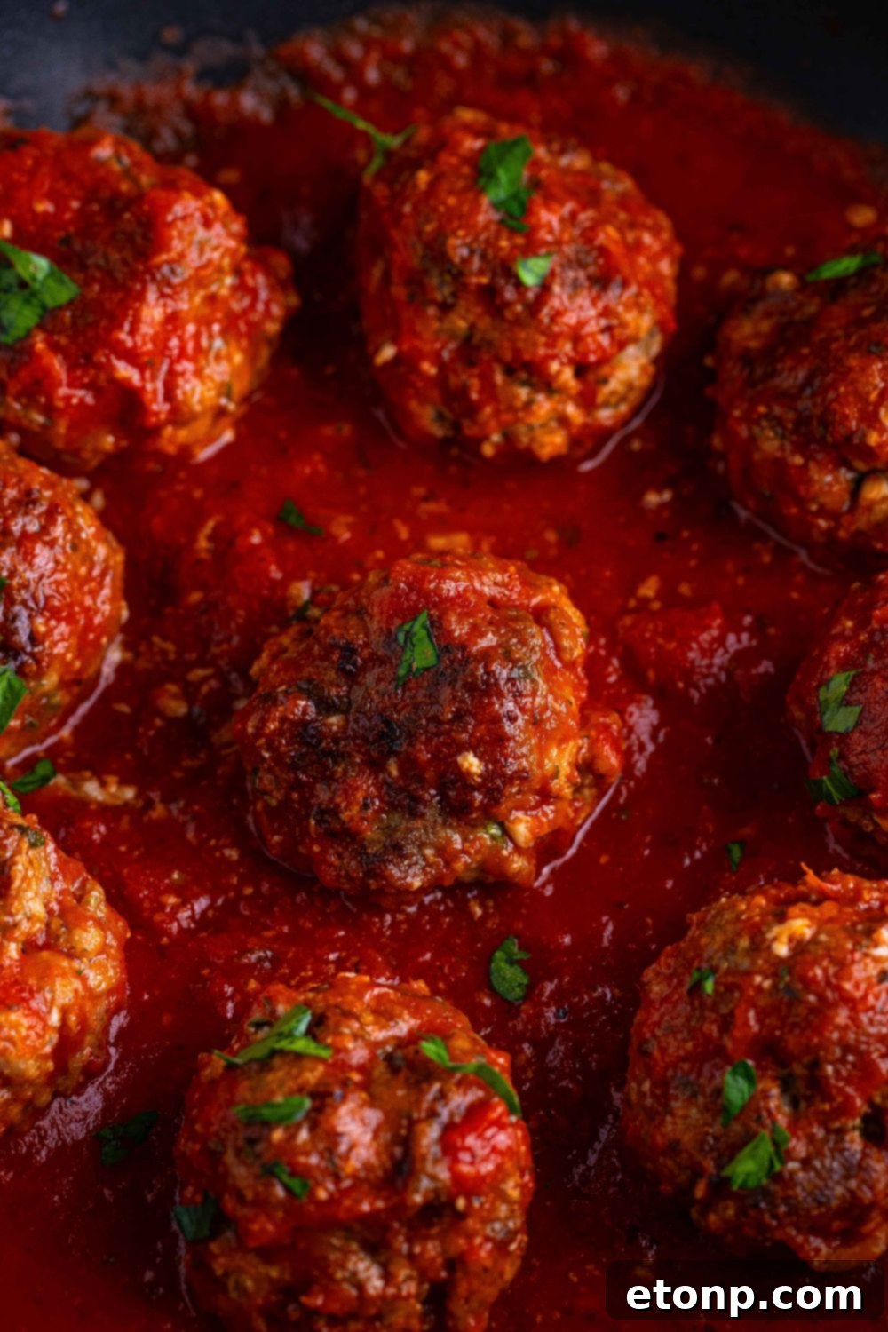 Classic Italian Meatballs close up in a pan with a marinara sauce drizzled on top 