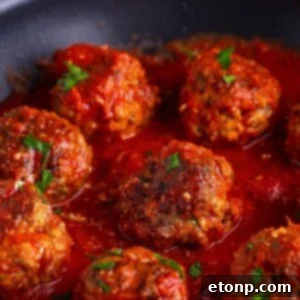 Classic Italian Meatballs in a pan with some sauce over the top of the meatballs