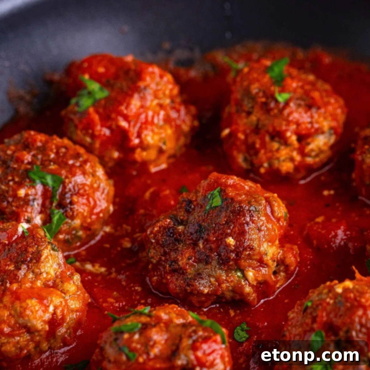 Classic Italian Meatballs in a pan with some sauce over the top of the meatballs 