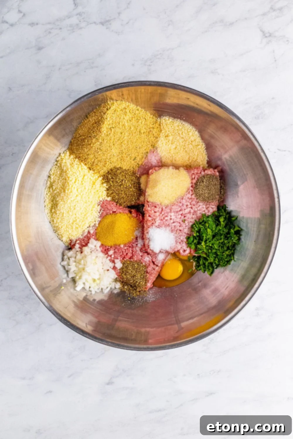 ingredients for the meatballs in a metal bowl on table 