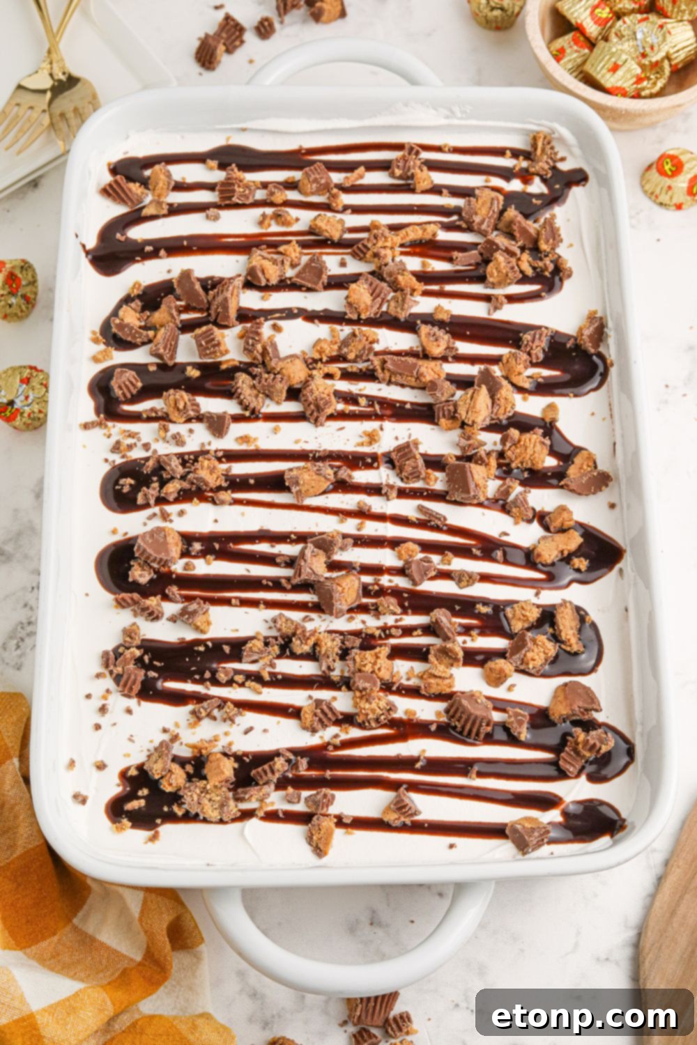 Reese's Peanut Butter Bliss Stack 14 An overhead shot of Reese's Lasagna in a white baking dish on a table, surrounded by scattered candies, ready to be enjoyed.