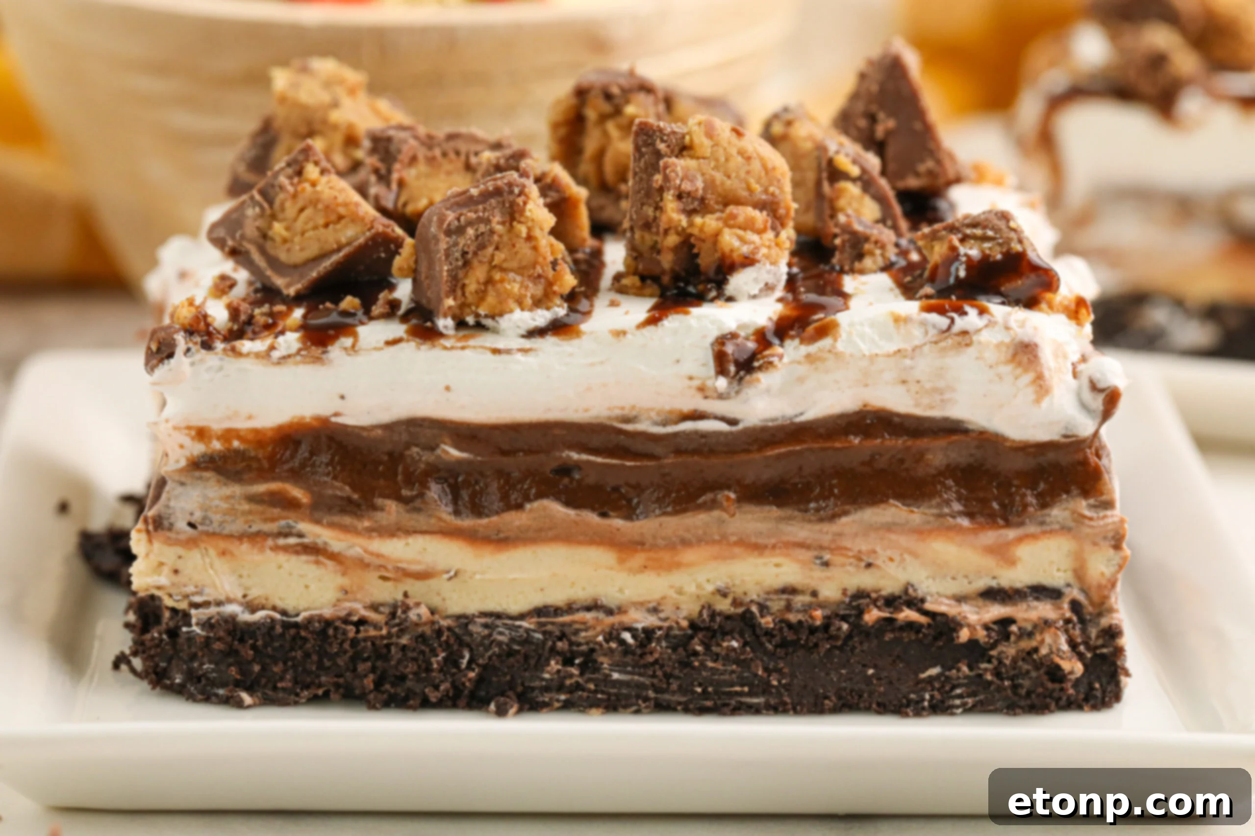 Reese's Peanut Butter Bliss Stack 16 A pristine white baking pan holds the completed Reese's Lasagna, with a perfectly formed piece being lifted out, showcasing its layered structure.