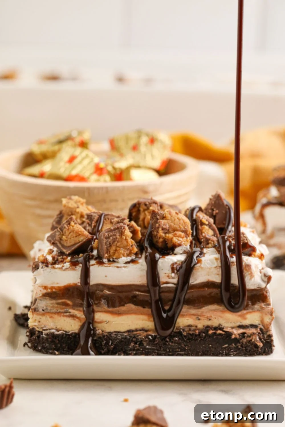 Reese's Peanut Butter Bliss Stack 20 A luscious chocolate sauce being artfully drizzled over a slice of Reese's Lasagna on a plate, adding a final touch of decadence.