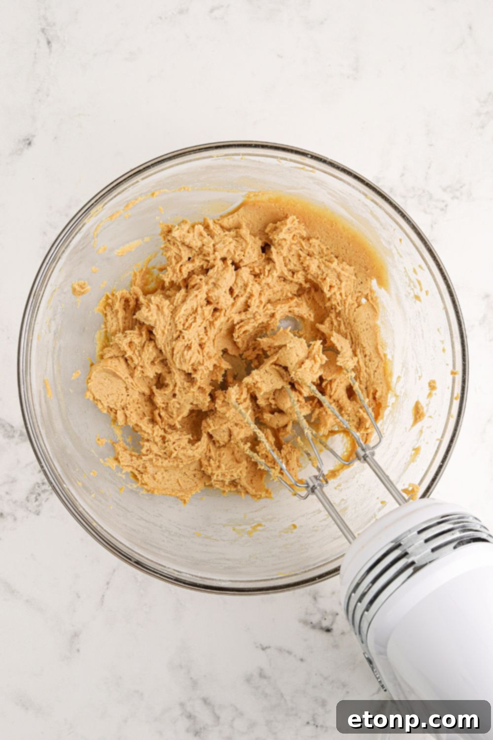 Reese's Peanut Butter Bliss Stack 7 A glass bowl containing a rich peanut butter mixture, being expertly mixed for the Reese's Lasagna.
