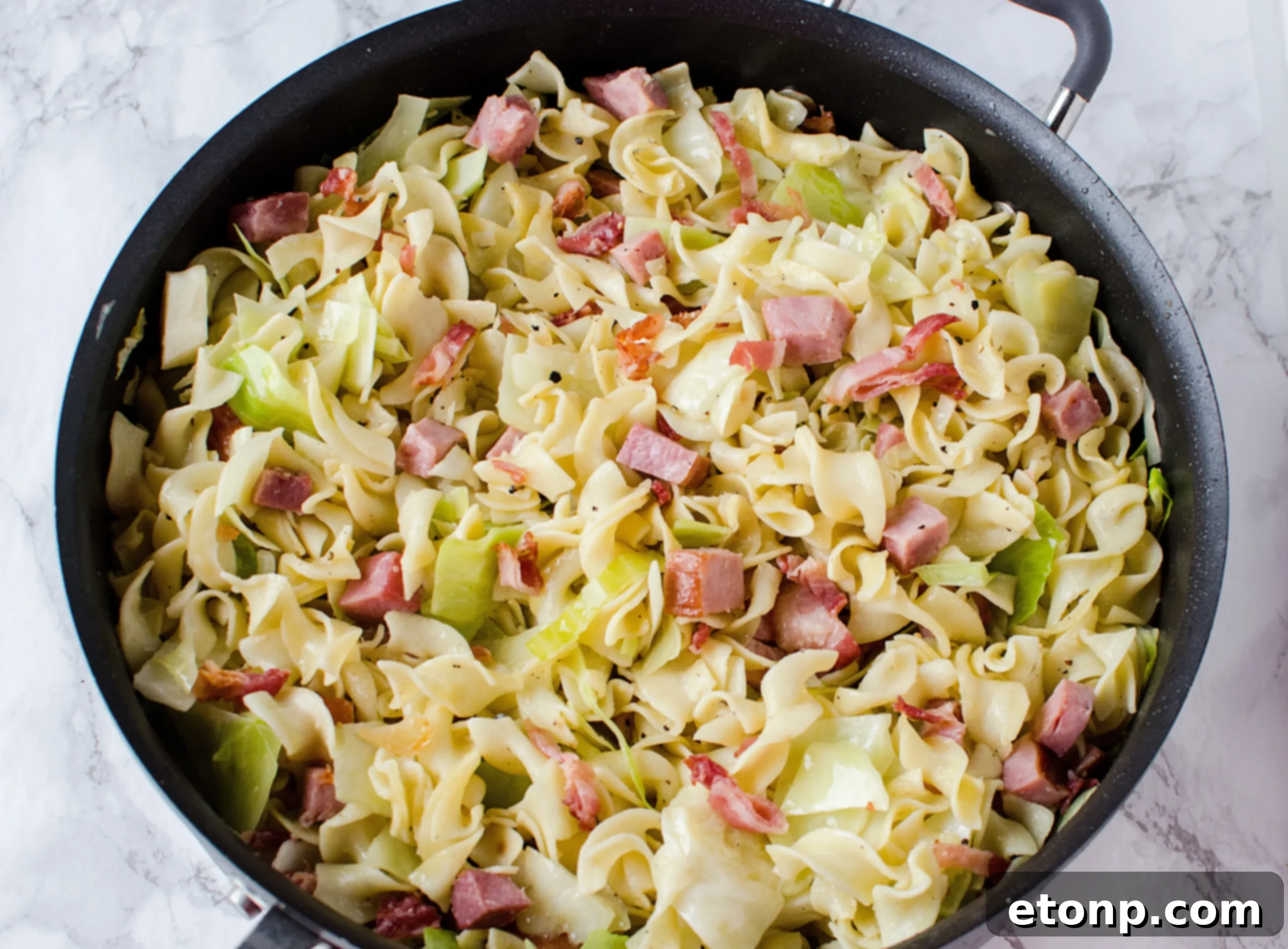A large skillet filled with sautéed cabbage and onions, releasing aromatic steam.