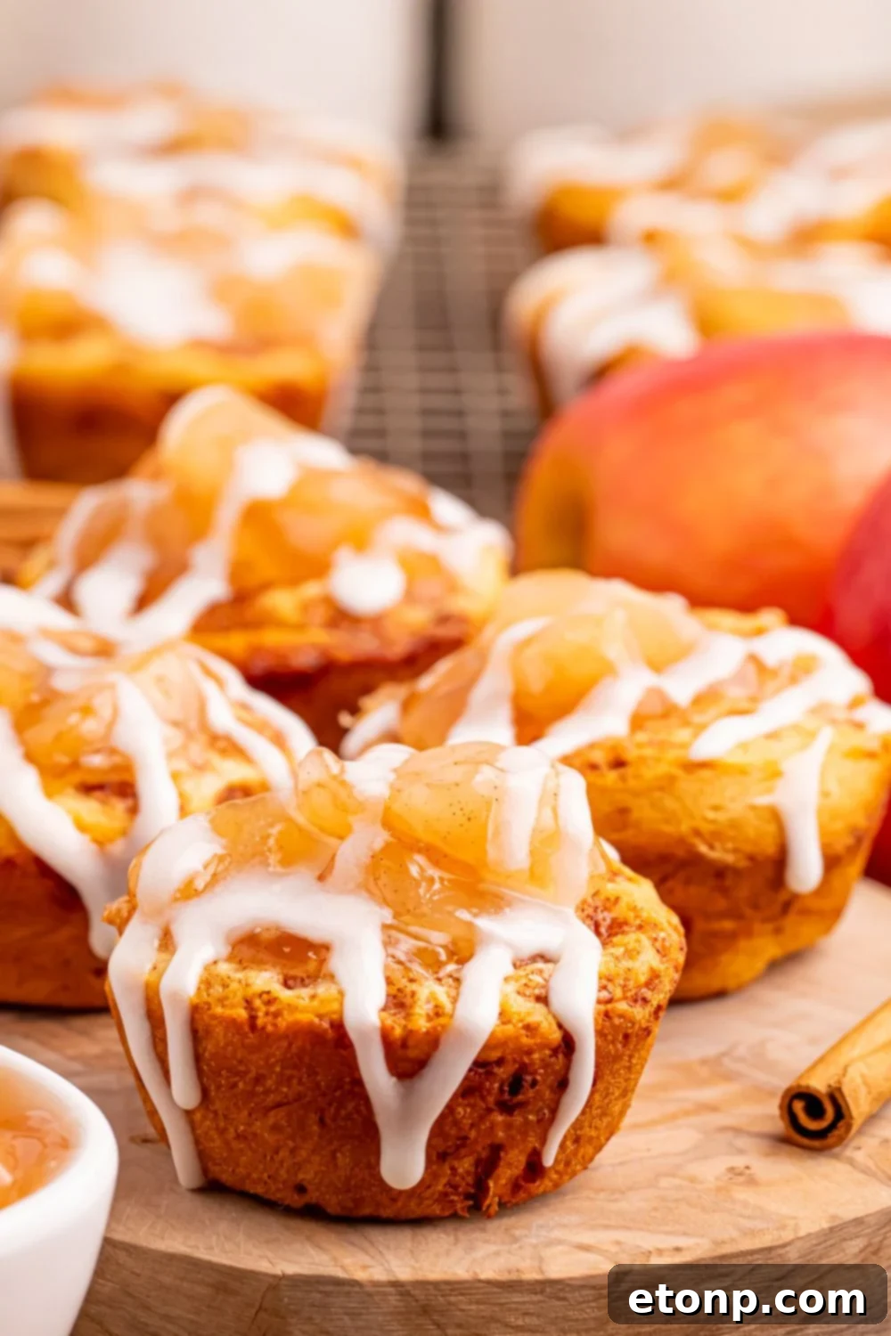 Effortless Apple Tartlets 2 Easy Apple Pie Cups on a round tray with more cups placed in the back of image with an apple to the side