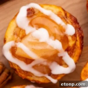 Effortless Apple Tartlets 15 overhead shot of an apple pie cup with a drizzle of icing on top sitting on a wooden cutting board on table