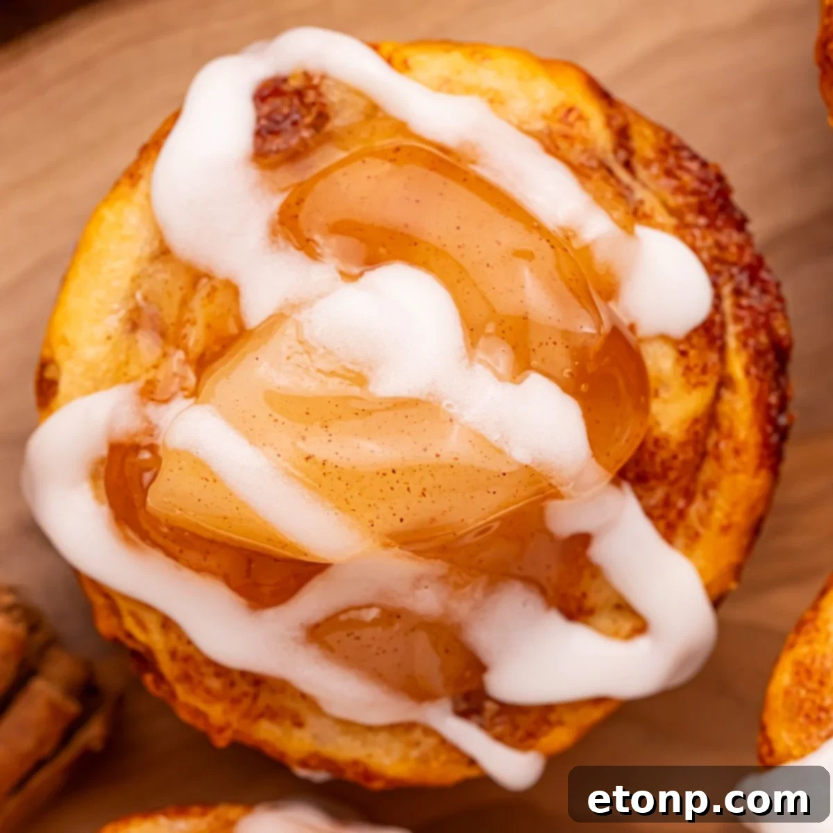 Effortless Apple Tartlets 3 overhead shot of an apple pie cup with a drizzle of icing on top sitting on a wooden cutting board on table