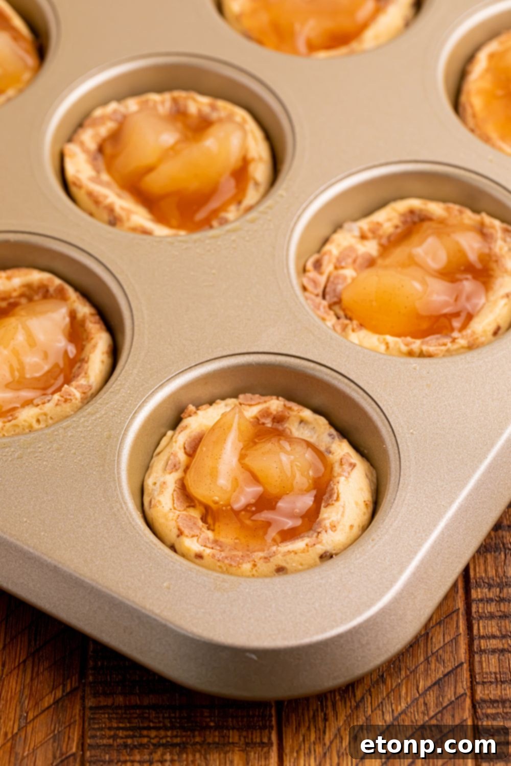 Effortless Apple Tartlets 8 raw Apple Pie Cups in muffin tin with some apple pie filling in center