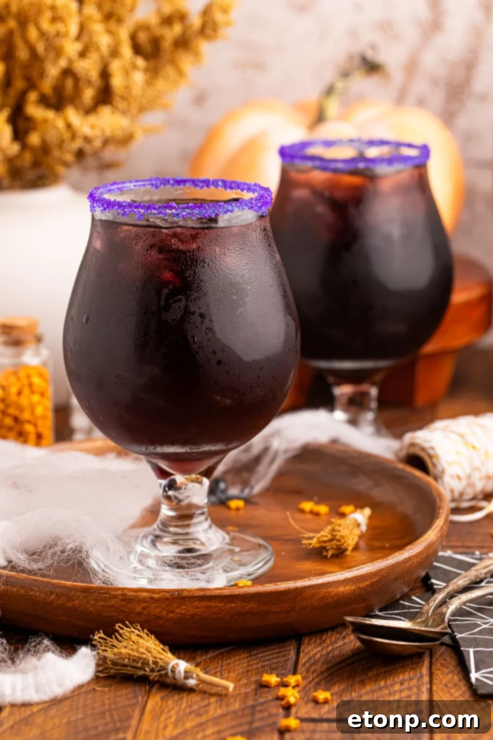 Witches Brew Cocktails sitting on table with a bunch of Halloween decor on table for a spooky vibe