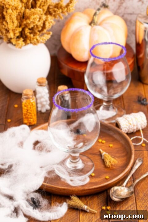 wine glasses sitting on a serving tray with Halloween sprinkles and more around the tray with wine glasses rimmed in sugar