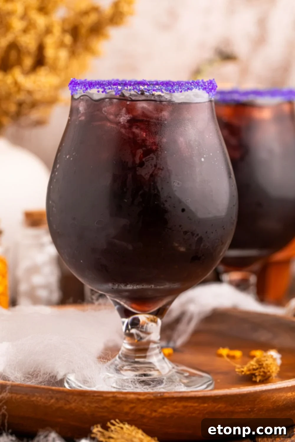 side view of glasses with a Witches Brew Cocktail in each of them sitting on a platter on table