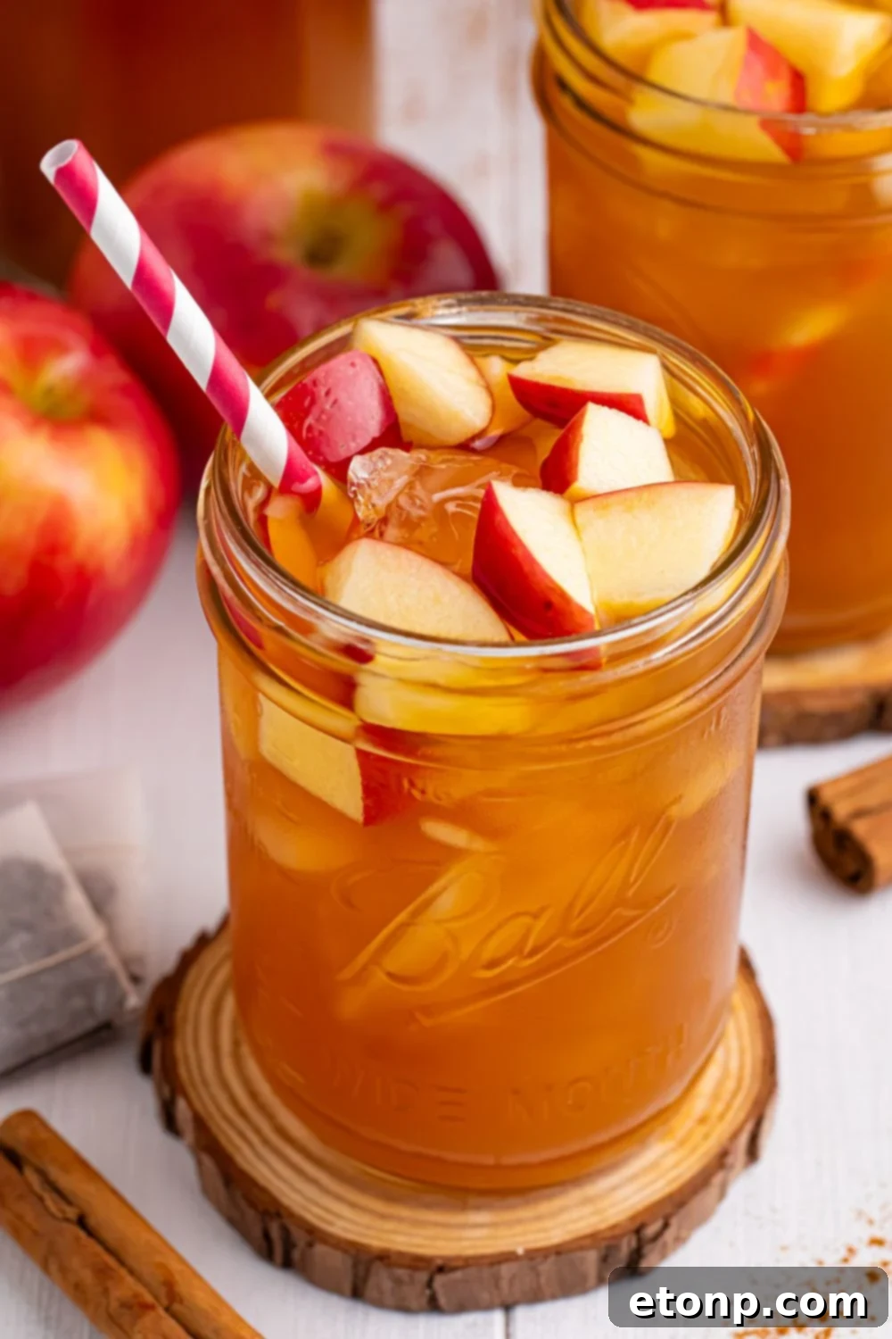 Orchard Apple Iced Tea 14 Apple Cider Iced Tea on table with a wooden cutting board under it and a straw sticking out the side