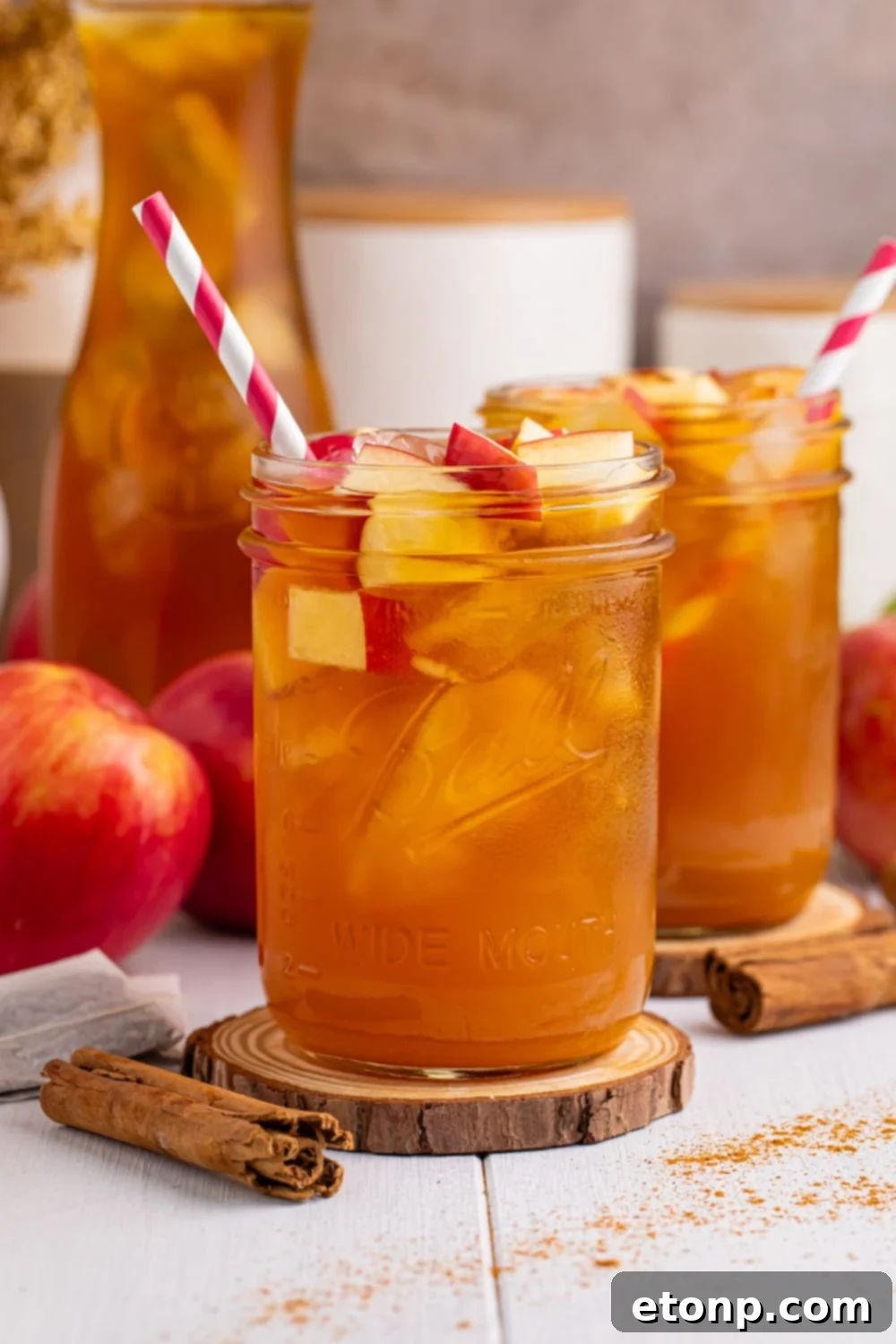 Orchard Apple Iced Tea 15 apple cider and tea in glasses on table with a sprinkle of cinnamon on table and apples