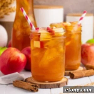 Orchard Apple Iced Tea 18 Apple Cider Iced Tea glasses on table with apples and cinnamon sticks around glasses and a red and white striped straw in each mason glass