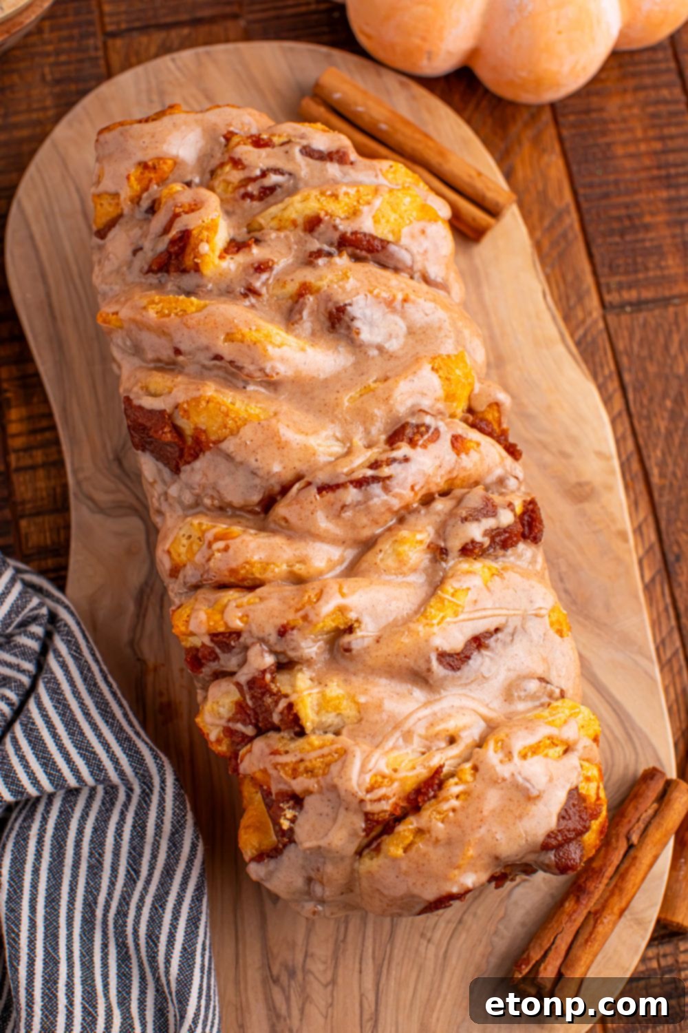 Golden Pumpkin Blossom Bread 15 Pumpkin Pie Pull Apart Bread on a cutting board with a fake pumpkin in the background and towel on side