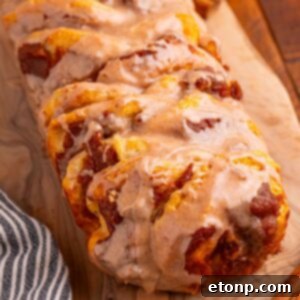 Golden Pumpkin Blossom Bread 20 Pumpkin Pie Pull Apart Bread on a cutting board sitting on table with glaze drizzled on top