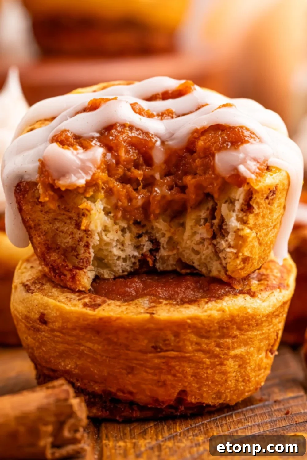 Several Pumpkin Pie Cinnamon Roll Cups stacked neatly on a table, highlighting their individual portion size and inviting texture.