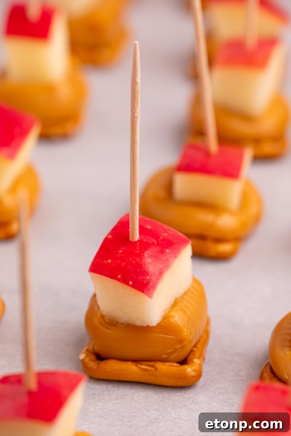 Sweet and Salty Caramel Apple Pretzel Bites 15 pretzel caramel bites with apples on top and toothpicks sitting on tray