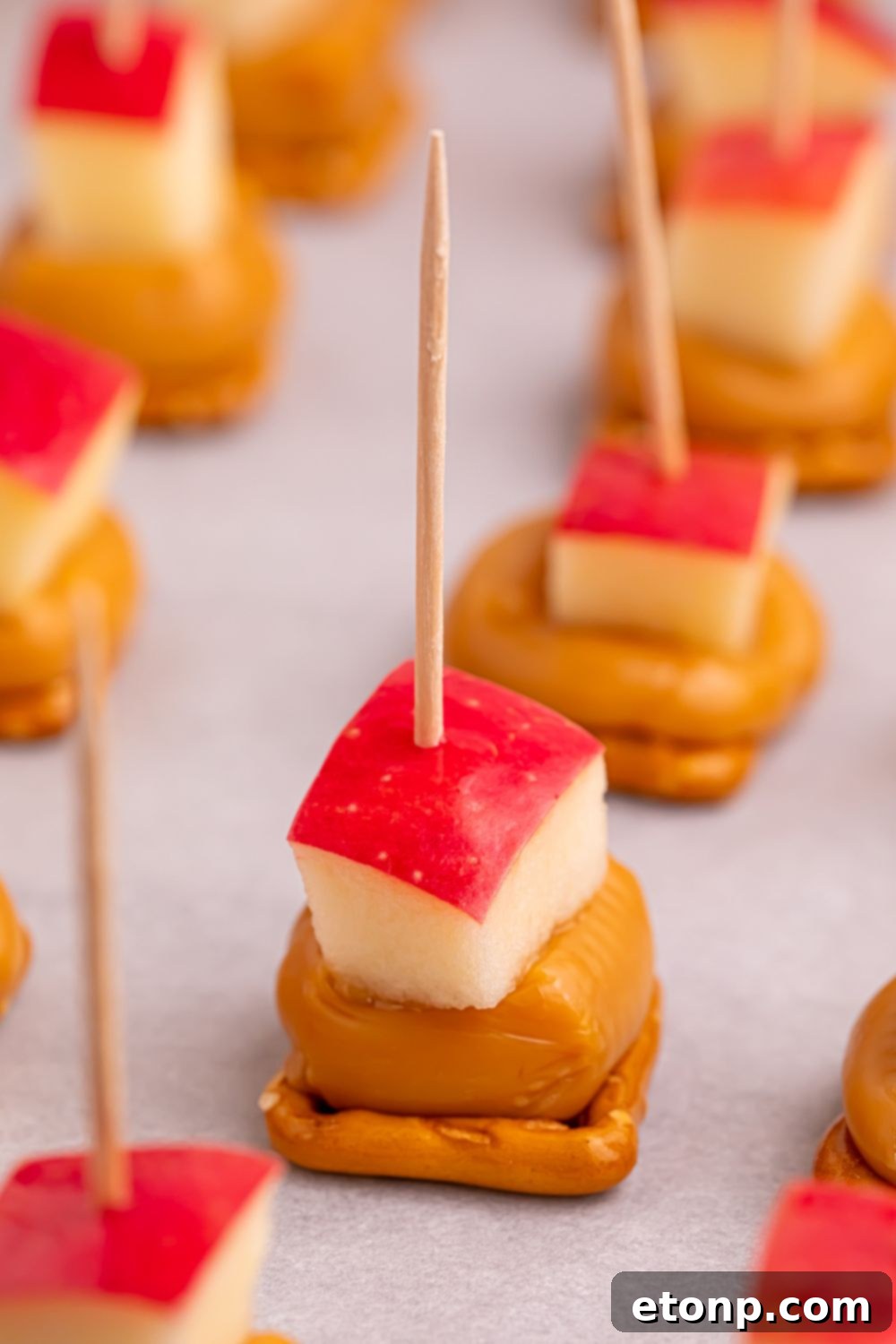 Sweet and Salty Caramel Apple Pretzel Bites 4 Caramel Apple Pretzel Bites on a parchment lined tray on table